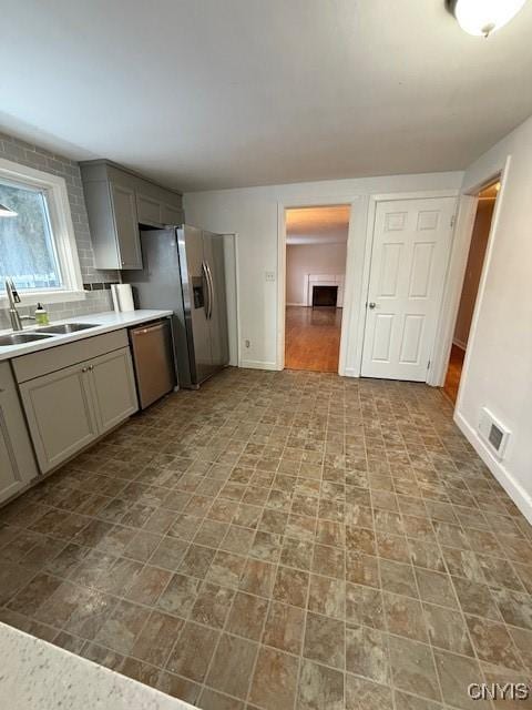 kitchen featuring gray cabinetry, sink, decorative backsplash, and appliances with stainless steel finishes