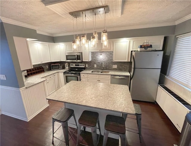 kitchen with a kitchen island, appliances with stainless steel finishes, pendant lighting, a breakfast bar, and sink