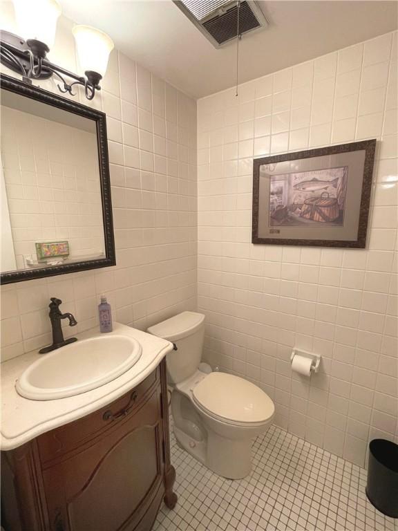 bathroom with vanity, toilet, tile patterned flooring, and tile walls