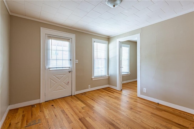 entryway with ornamental molding and light hardwood / wood-style floors