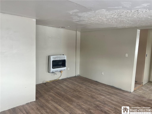 spare room with heating unit and wood-type flooring