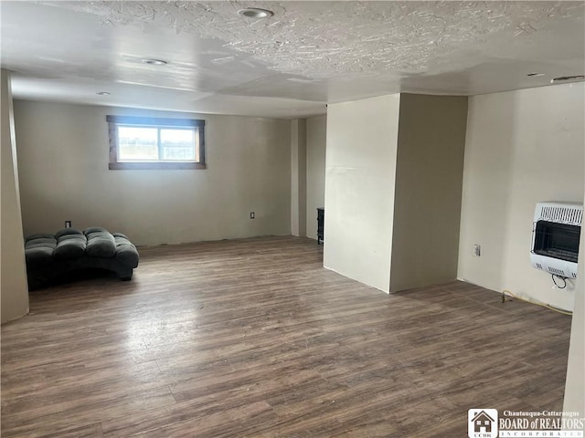 interior space featuring dark hardwood / wood-style floors, heating unit, and a textured ceiling