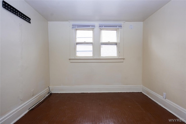 spare room featuring wood-type flooring and baseboards