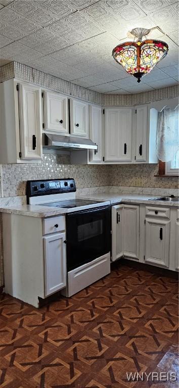 kitchen with under cabinet range hood, white cabinets, electric range oven, and light countertops