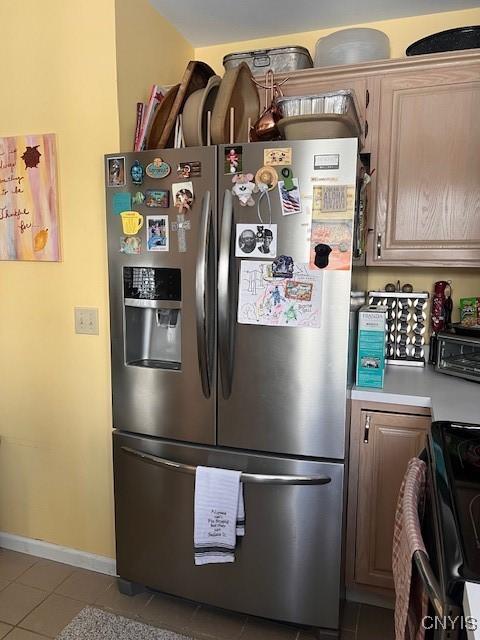 kitchen with stainless steel refrigerator with ice dispenser, light tile patterned flooring, and range with electric stovetop