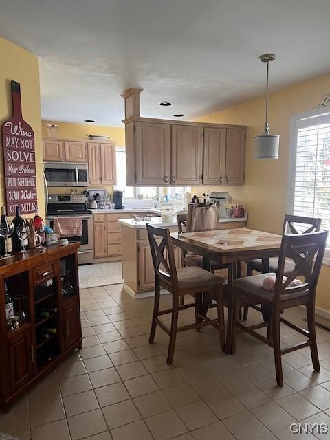 kitchen featuring pendant lighting, light brown cabinetry, light tile patterned floors, and appliances with stainless steel finishes