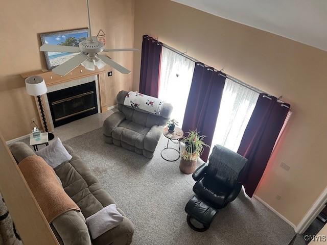 living room with a tile fireplace, ceiling fan, and carpet flooring