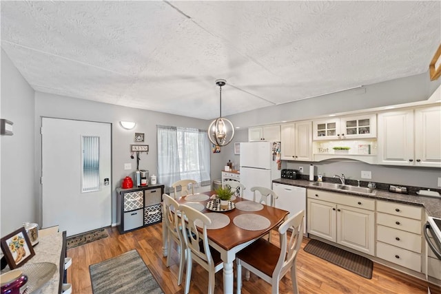 dining room featuring sink, a chandelier, a textured ceiling, and light hardwood / wood-style floors