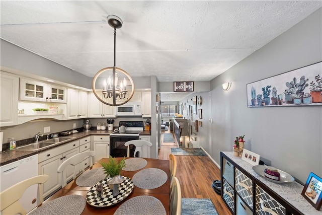 kitchen with sink, white cabinets, hanging light fixtures, a notable chandelier, and white appliances