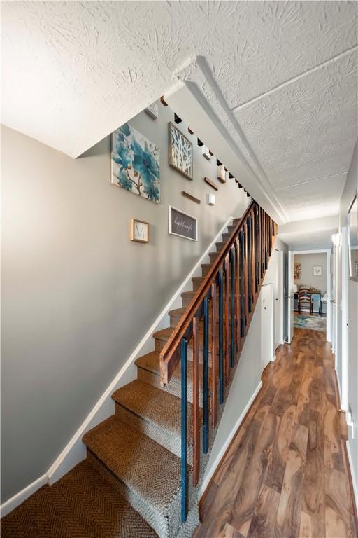 stairway with hardwood / wood-style floors and a textured ceiling