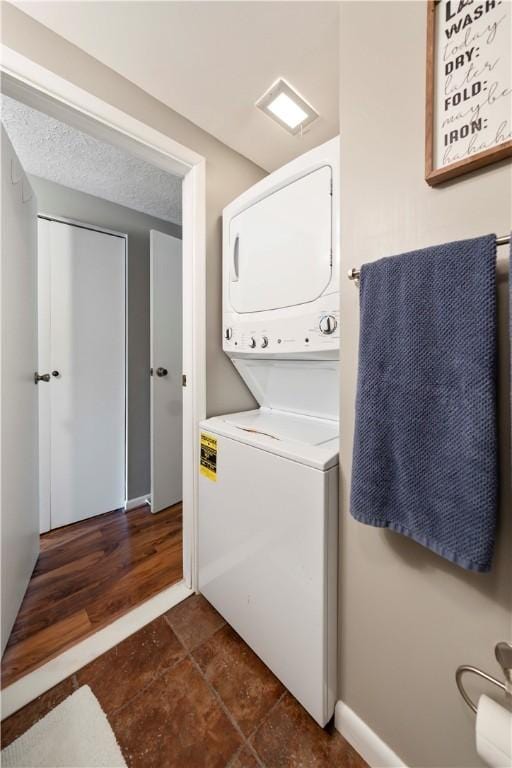 washroom with a textured ceiling and stacked washer / dryer