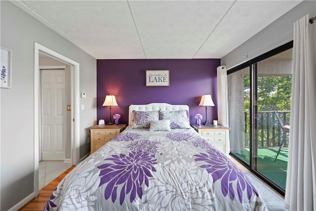 bedroom featuring access to outside, a textured ceiling, and light hardwood / wood-style flooring