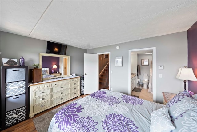 bedroom with ensuite bathroom and hardwood / wood-style floors