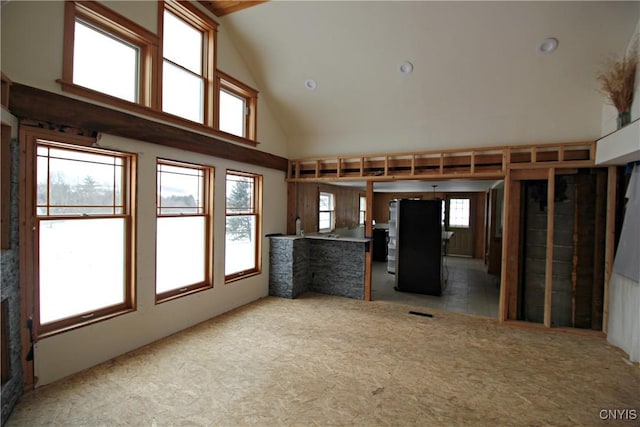 unfurnished living room with carpet flooring and high vaulted ceiling