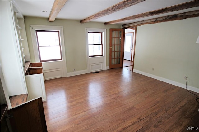 unfurnished room featuring beam ceiling and light hardwood / wood-style flooring