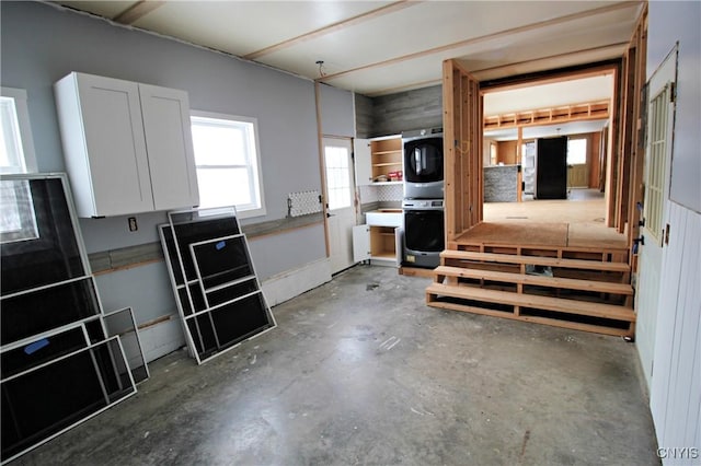 interior space with sink, concrete flooring, and stacked washing maching and dryer