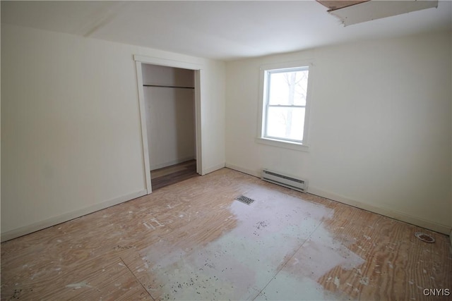 unfurnished bedroom with a baseboard heating unit and a closet