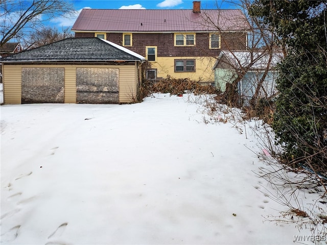 snow covered back of property with a garage