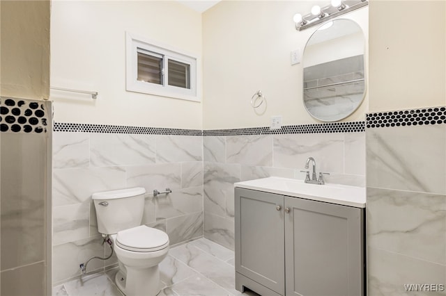 bathroom featuring vanity, tile walls, and toilet