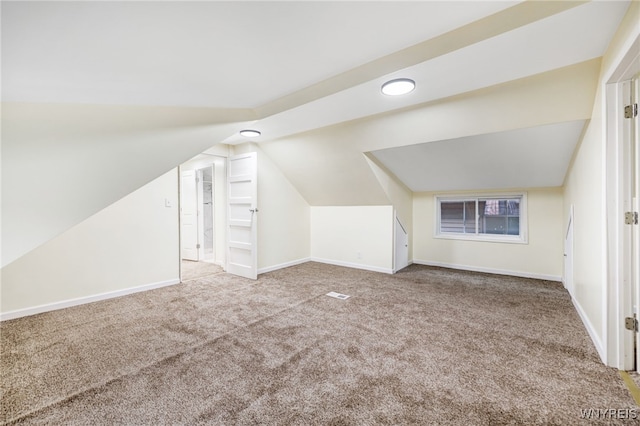 bonus room with vaulted ceiling and light carpet