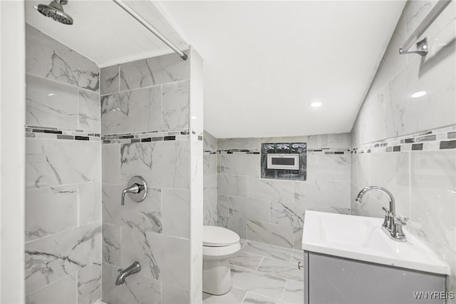 bathroom featuring tile walls, vanity, toilet, and a tile shower