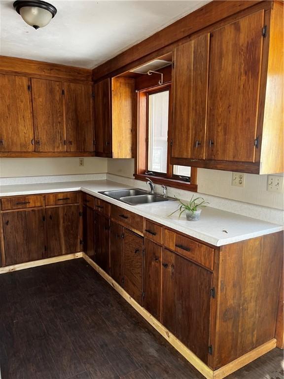 kitchen featuring light countertops, dark wood-style flooring, and a sink