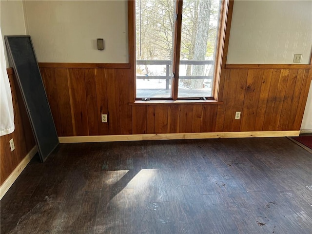 unfurnished room with hardwood / wood-style floors, wooden walls, and a wainscoted wall