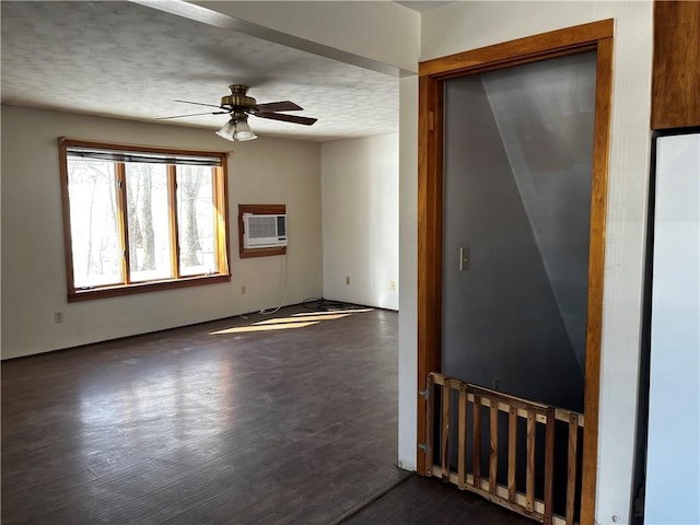 empty room featuring ceiling fan, dark wood-type flooring, a wall mounted AC, and a textured ceiling