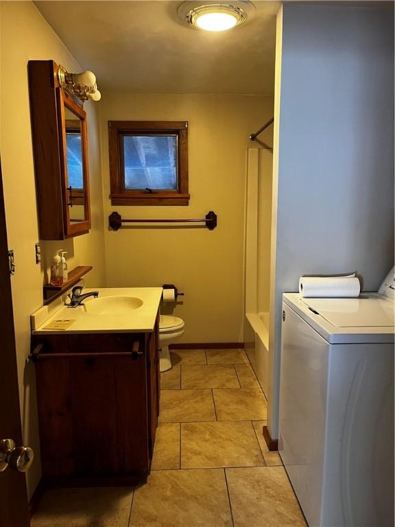 full bath featuring vanity, tile patterned flooring, toilet, baseboards, and washing machine and dryer