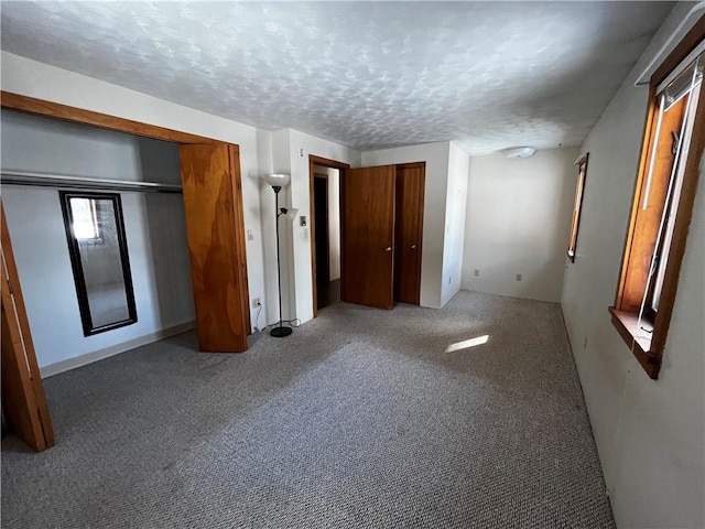 unfurnished bedroom featuring carpet flooring, two closets, and a textured ceiling