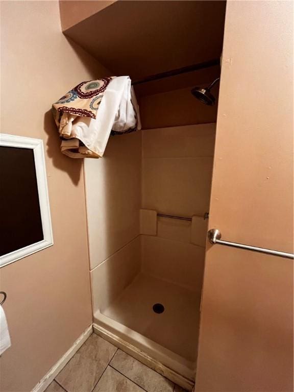 bathroom with a shower, tile patterned floors, and baseboards