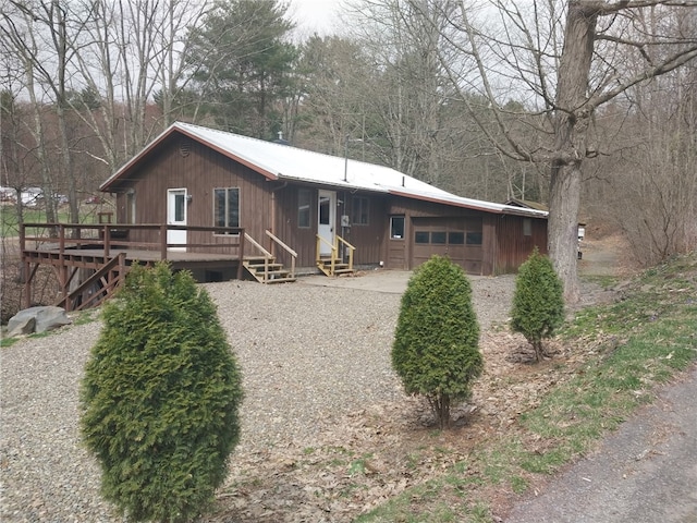 chalet / cabin with entry steps, a garage, a wooden deck, and metal roof