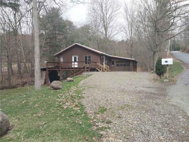 view of front of house featuring a wooded view, gravel driveway, and a deck