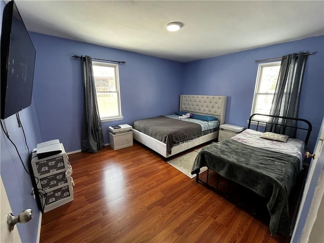 bedroom with multiple windows and dark hardwood / wood-style floors