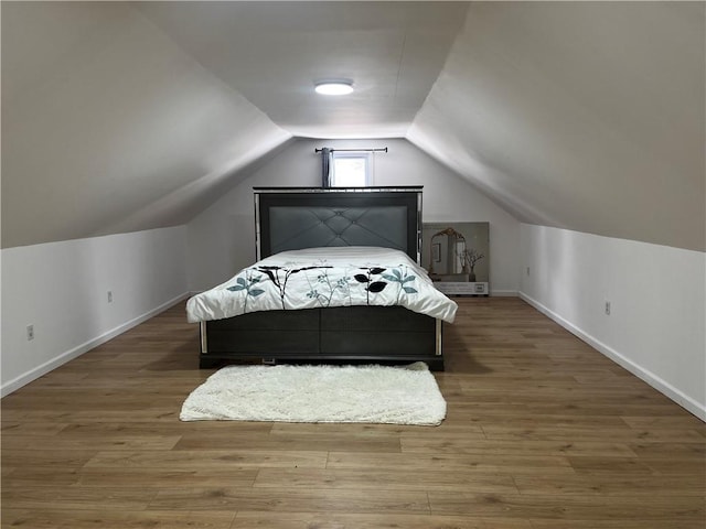 bedroom with wood-type flooring and vaulted ceiling