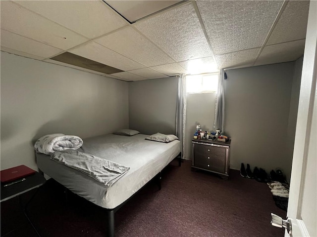 bedroom featuring a paneled ceiling and dark carpet