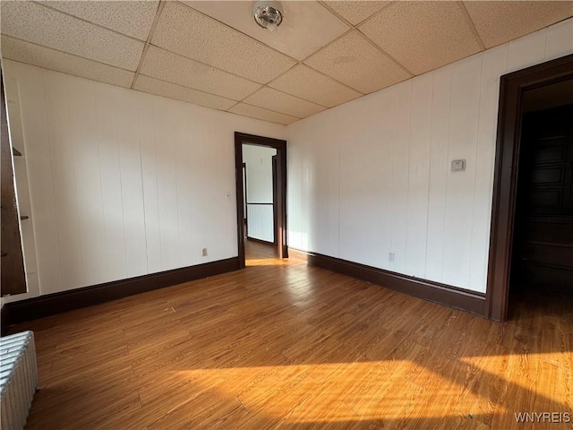 empty room featuring hardwood / wood-style flooring, radiator heating unit, and a paneled ceiling