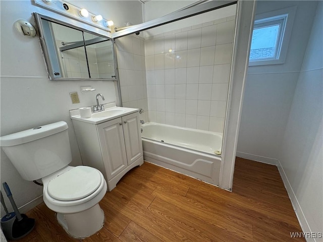 full bathroom with hardwood / wood-style flooring, tiled shower / bath, vanity, and toilet