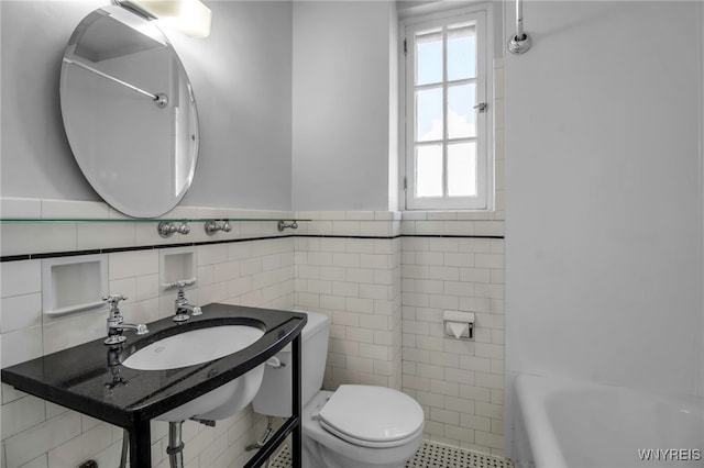 bathroom with tile walls, sink, and toilet