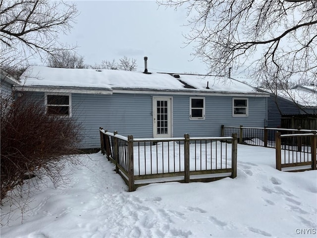 snow covered rear of property with a wooden deck