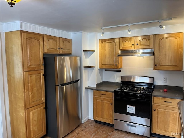 kitchen with stainless steel refrigerator, gas range oven, and dark tile patterned flooring