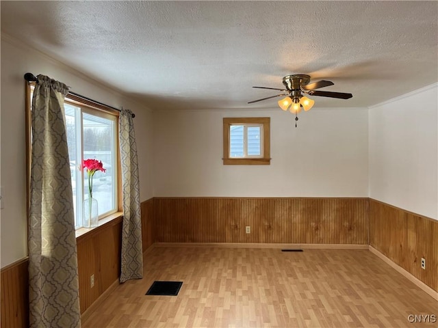 unfurnished room with light hardwood / wood-style flooring, a textured ceiling, and wood walls