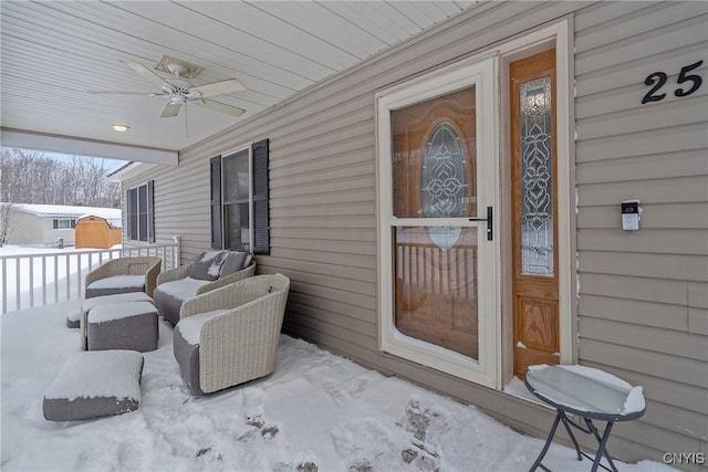 snow covered property entrance featuring ceiling fan and a porch