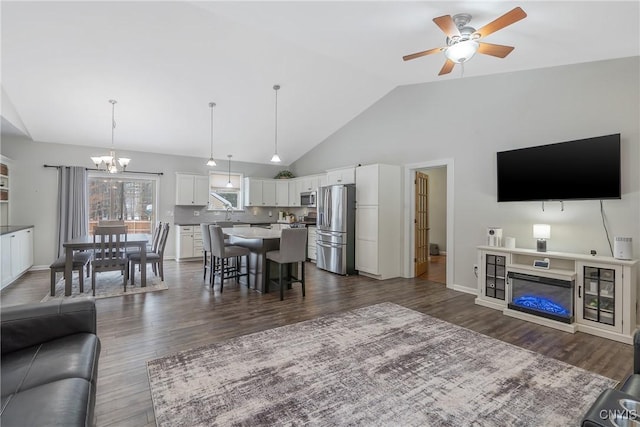 living room featuring sink, high vaulted ceiling, dark hardwood / wood-style floors, and ceiling fan with notable chandelier