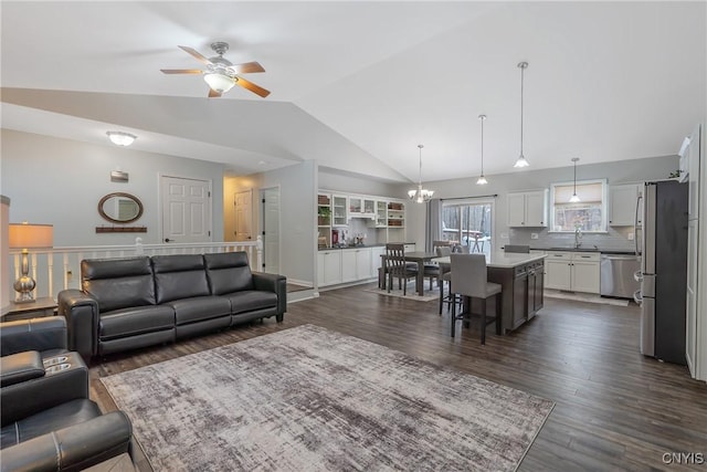 living room with high vaulted ceiling, ceiling fan with notable chandelier, and dark hardwood / wood-style flooring