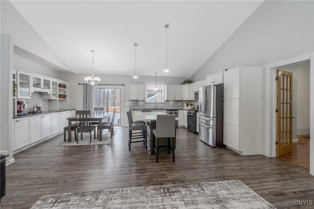 dining area with dark wood-type flooring, high vaulted ceiling, and a notable chandelier