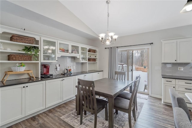 dining space with vaulted ceiling, dark hardwood / wood-style floors, and a notable chandelier