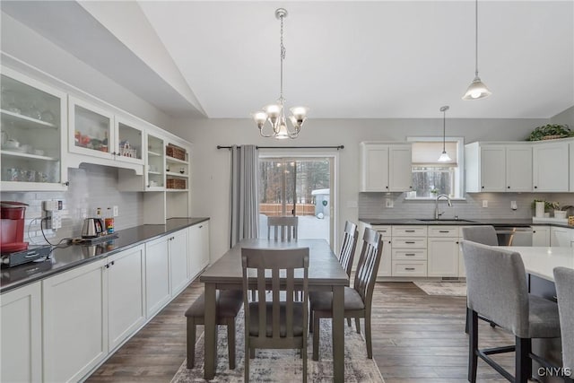 dining room featuring lofted ceiling, dark hardwood / wood-style flooring, sink, and a notable chandelier