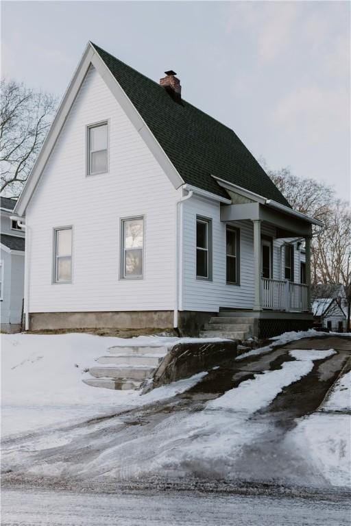 exterior space with covered porch, roof with shingles, and a chimney