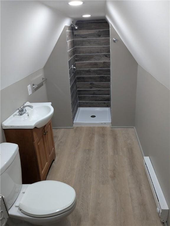 bathroom featuring a stall shower, a baseboard radiator, wood finished floors, and toilet